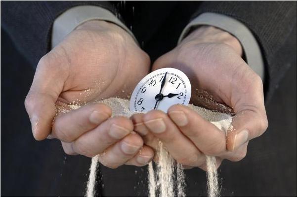 Hands holding time piece in sand